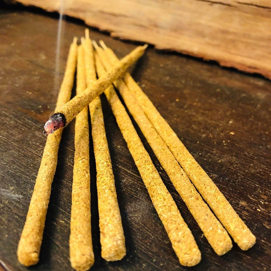 Palo Santo incense sticks alight on a wooden board